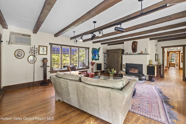 253 Upper Byrdcliffe Rd, Woodstock, NY 12498 - living area with wood finished floors, baseboards, a glass covered fireplace, beam ceiling, and a wall mounted AC