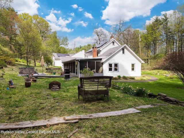 236 Spillway Rd, West Hurley, NY 12491 - back of property with a sunroom, an outdoor fire pit, solar panels, a lawn, and a chimney
