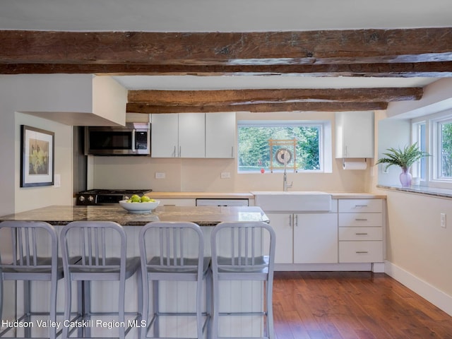 236 Spillway Rd, West Hurley, NY 12491 - kitchen with stainless steel appliances, a sink, white cabinets, a kitchen breakfast bar, and dark wood-style flooring