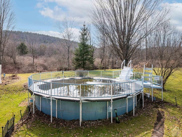 view of swimming pool featuring a covered pool, a water slide, and fence