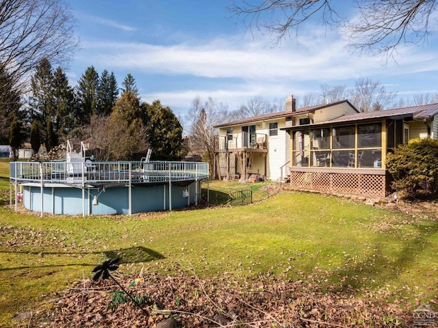 view of green lawn featuring a sunroom and an outdoor pool