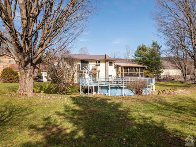 rear view of property featuring a sunroom, a yard, a covered pool, metal roof, and a chimney