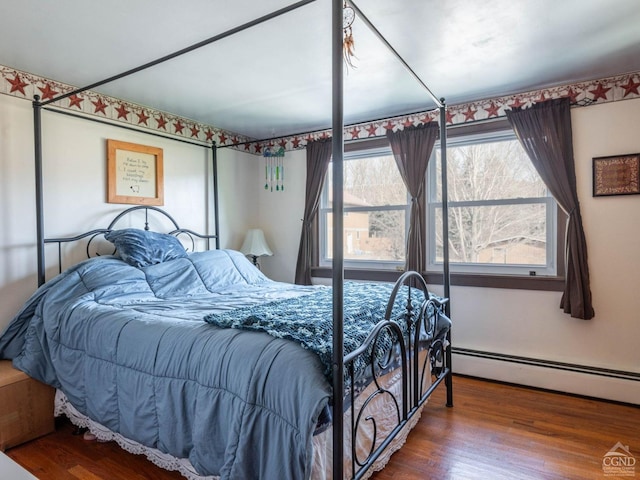 bedroom with wood finished floors and a baseboard heating unit
