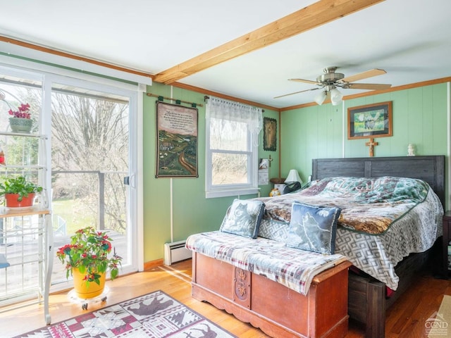 bedroom featuring a baseboard heating unit, multiple windows, wood finished floors, crown molding, and a ceiling fan