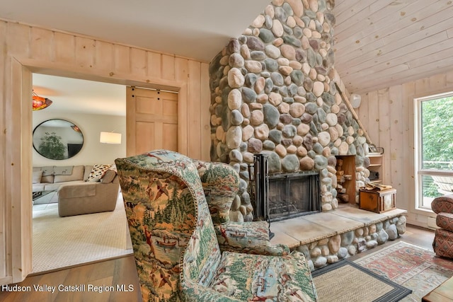 122 Brainard Ridge Rd Unit 14F, Windham, NY 12496 - living room with a barn door, wooden walls, wood finished floors, a stone fireplace, and vaulted ceiling