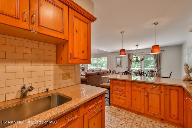 122 Brainard Ridge Rd Unit 14F, Windham, NY 12496 - kitchen featuring brown cabinetry, tasteful backsplash, pendant lighting, and light stone counters