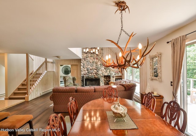 122 Brainard Ridge Rd Unit 14F, Windham, NY 12496 - dining area featuring stairs, wood finished floors, a chandelier, a stone fireplace, and a baseboard heating unit