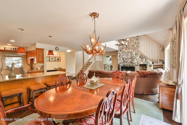 122 Brainard Ridge Rd Unit 14F, Windham, NY 12496 - dining area featuring vaulted ceiling, a stone fireplace, a chandelier, and stairway