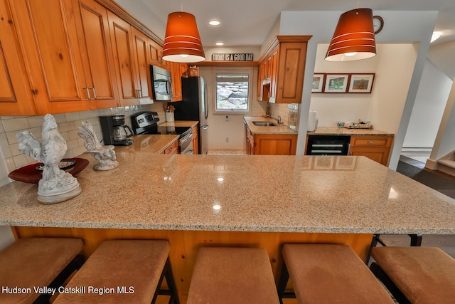 122 Brainard Ridge Rd Unit 14F, Windham, NY 12496 - kitchen featuring appliances with stainless steel finishes, brown cabinets, tasteful backsplash, wine cooler, and light stone counters