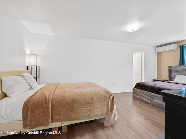 bedroom featuring hardwood / wood-style floors and an AC wall unit