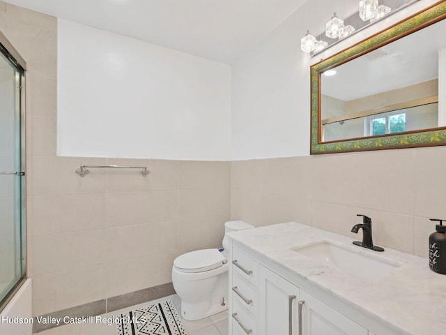 bathroom with tile patterned floors, vanity, toilet, and tile walls