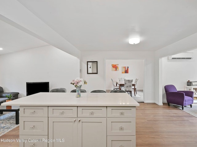 kitchen featuring a kitchen bar, a wall mounted AC, a center island, and light wood-type flooring