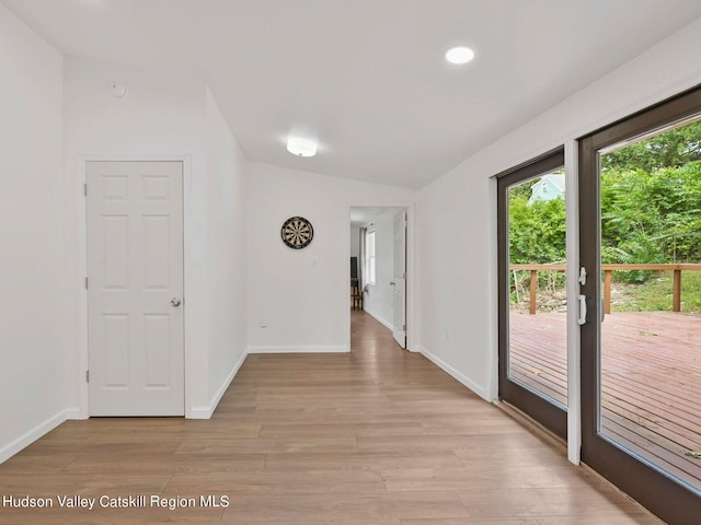 corridor with lofted ceiling and light hardwood / wood-style flooring