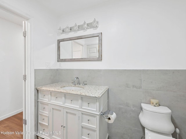 bathroom featuring hardwood / wood-style flooring, vanity, toilet, and tile walls