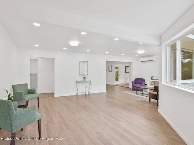 living area with an AC wall unit and light hardwood / wood-style flooring