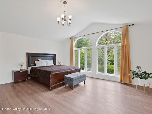 bedroom featuring a chandelier, lofted ceiling, and light wood-type flooring