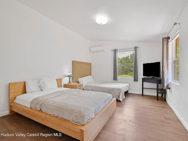 bedroom with a wall unit AC, lofted ceiling, and hardwood / wood-style flooring