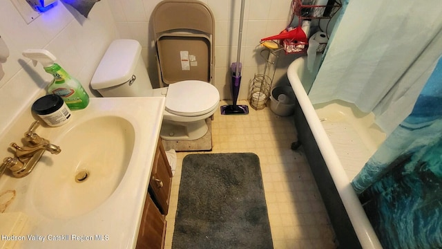 bathroom with vanity, toilet, and tile walls