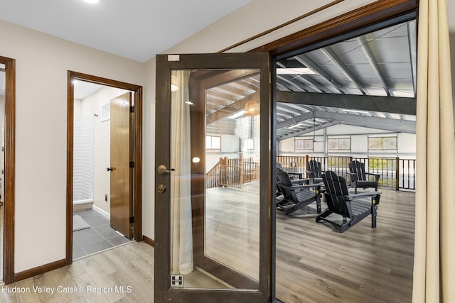 entryway featuring lofted ceiling, baseboards, and wood finished floors