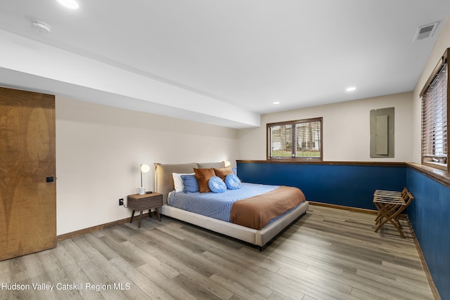 bedroom with baseboards, wood finished floors, and multiple windows