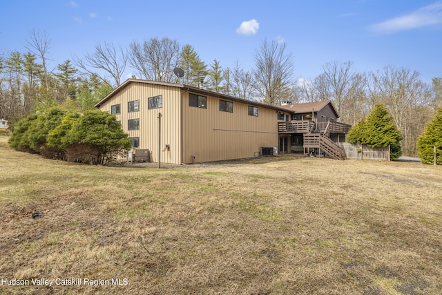 rear view of property with a wooden deck, a yard, and stairs