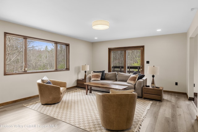 living room with plenty of natural light, baseboards, and light wood-style floors