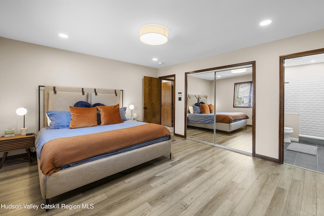 bedroom with light wood finished floors, ensuite bathroom, baseboards, recessed lighting, and a closet