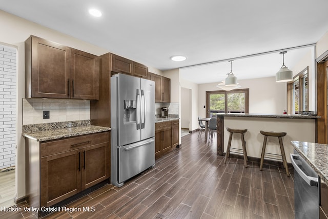 kitchen featuring decorative backsplash, hanging light fixtures, appliances with stainless steel finishes, and dark wood finished floors