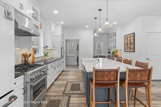 kitchen with pendant lighting, white cabinetry, an island with sink, a kitchen bar, and stainless steel appliances