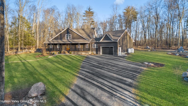 view of front of house featuring board and batten siding, a front lawn, a porch, driveway, and an attached garage