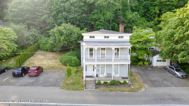 view of front of property featuring a garage, covered porch, an outdoor structure, and a balcony