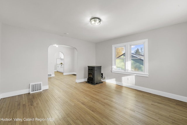 unfurnished living room with light wood-type flooring and a wood stove