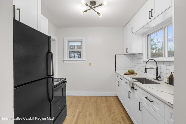 kitchen featuring white cabinets, light wood-type flooring, a wealth of natural light, and black appliances