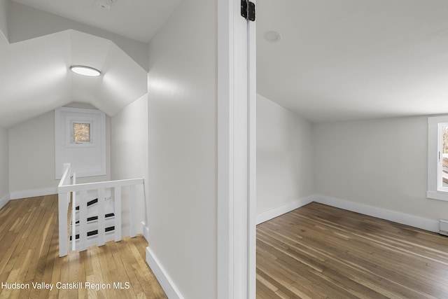 additional living space with hardwood / wood-style floors and lofted ceiling