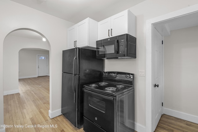 kitchen with white cabinetry, black appliances, and light hardwood / wood-style floors