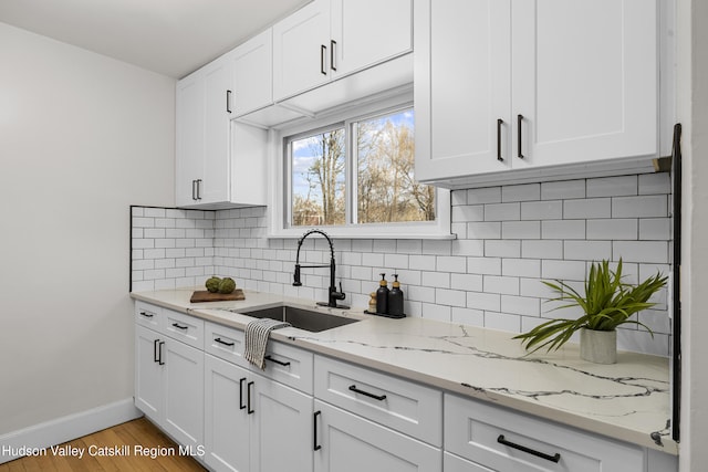 kitchen featuring tasteful backsplash, white cabinetry, sink, and light hardwood / wood-style floors