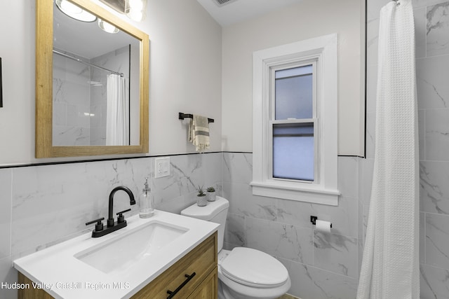 bathroom featuring walk in shower, vanity, toilet, and tile walls