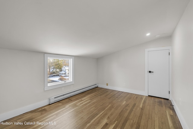 empty room with hardwood / wood-style floors, lofted ceiling, and a baseboard radiator