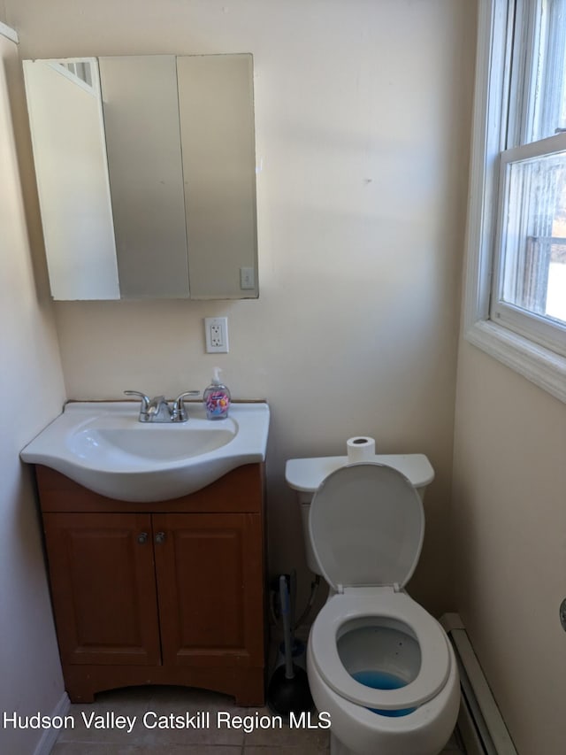 bathroom with tile patterned flooring, toilet, vanity, and a baseboard heating unit