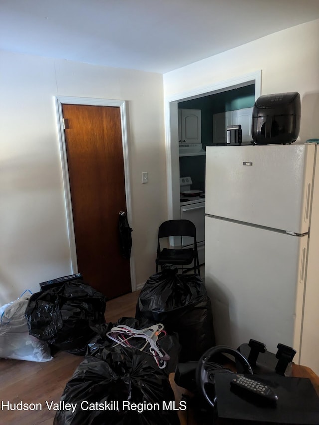 kitchen with stove, white fridge, and hardwood / wood-style flooring