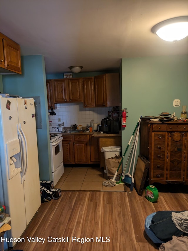 kitchen with sink, white appliances, light hardwood / wood-style flooring, and backsplash