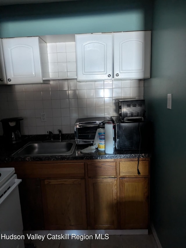 kitchen with white cabinets, electric range, tasteful backsplash, and sink