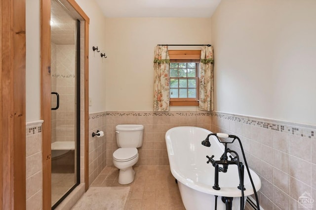 19 Twin Maples Ln, Windham, NY 12496 - bathroom with tile walls, a wainscoted wall, a shower stall, a soaking tub, and toilet