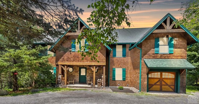 19 Twin Maples Ln, Windham, NY 12496 - view of front of property with covered porch, a shingled roof, driveway, and a garage