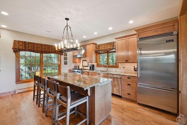 19 Twin Maples Ln, Windham, NY 12496 - kitchen featuring appliances with stainless steel finishes, wall chimney exhaust hood, a center island, light stone countertops, and a sink