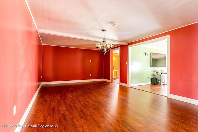 spare room with hardwood / wood-style floors and a chandelier