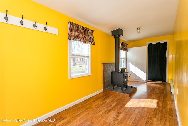 workout area with hardwood / wood-style floors, a wood stove, and baseboard heating