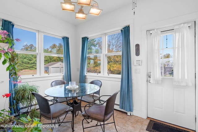 dining space featuring a baseboard heating unit, an inviting chandelier, and a healthy amount of sunlight