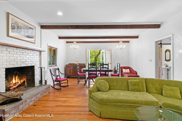 living room featuring hardwood / wood-style floors, beam ceiling, a fireplace, and a chandelier