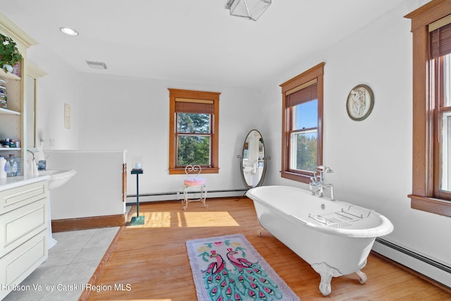 bathroom featuring hardwood / wood-style floors, vanity, a baseboard radiator, and a tub